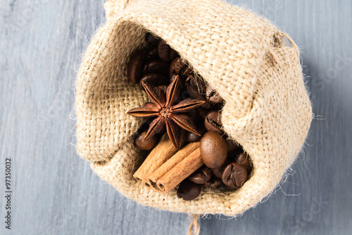 Coffee beans, star anise and cinnamon in bag on gray wooden table
