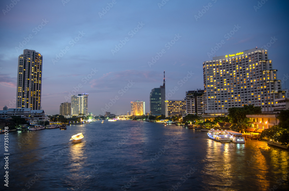 Bangkok cityscape with river and boat at night time . Chao Phray