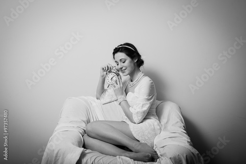 Elegant beautiful young lady having fun holding alarm clock and happy smile on copy space background. Black and white photography