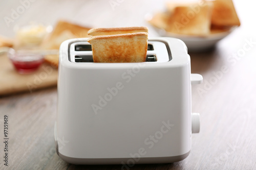 A couple of crusty toast in the toaster on the table, close-up