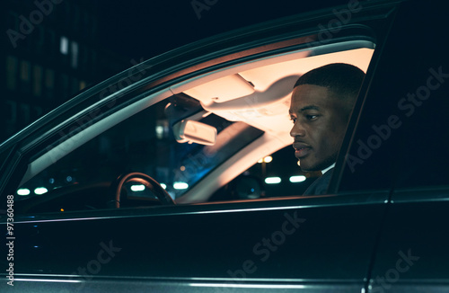 Side view of young man in car at night.