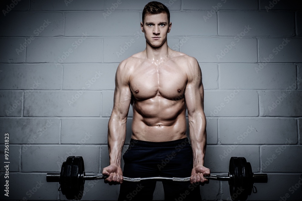 Athletic man doing exercises with barbell in The Gym's Studio Athletic man doing exercises with barbell in The Gym's Studio