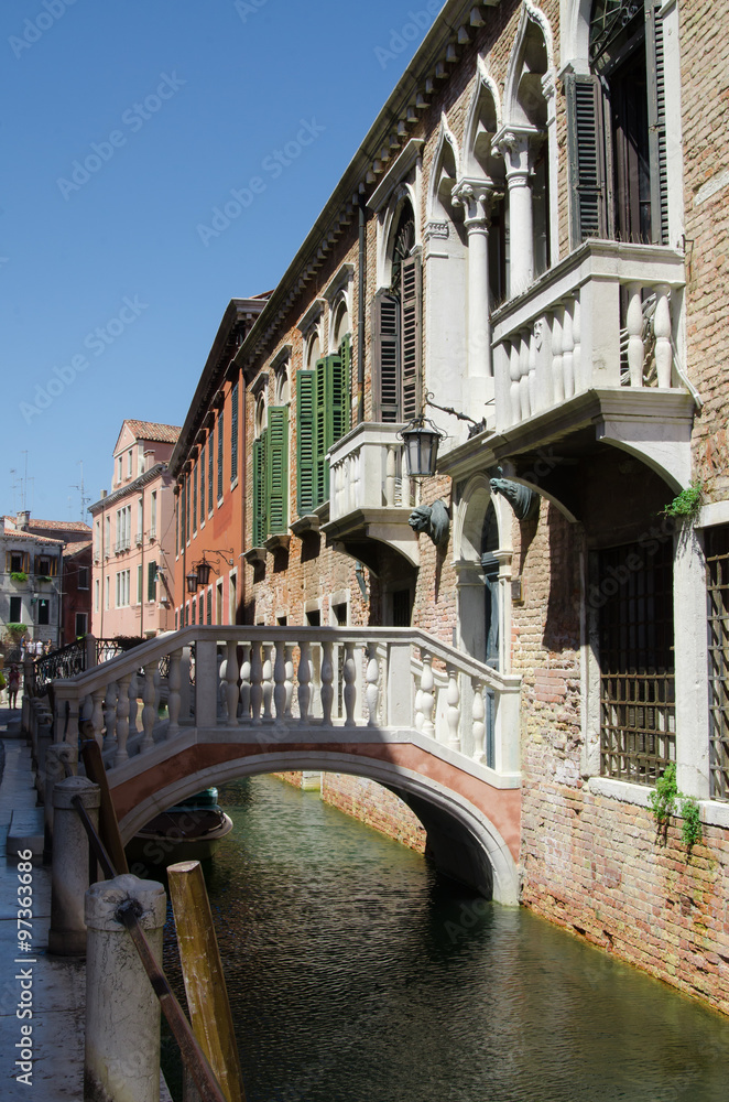 Canal  in Venice - old buildings, raw walls, closed shutters and doors near the water