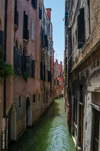 Canal in Venice - old buildings, raw walls, closed shutters and doors near the water