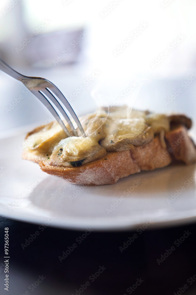 Fork on bruschetta mushrooms and cheese on bread with smoke Fork on bruschetta mushrooms and cheese on bread with smoke
