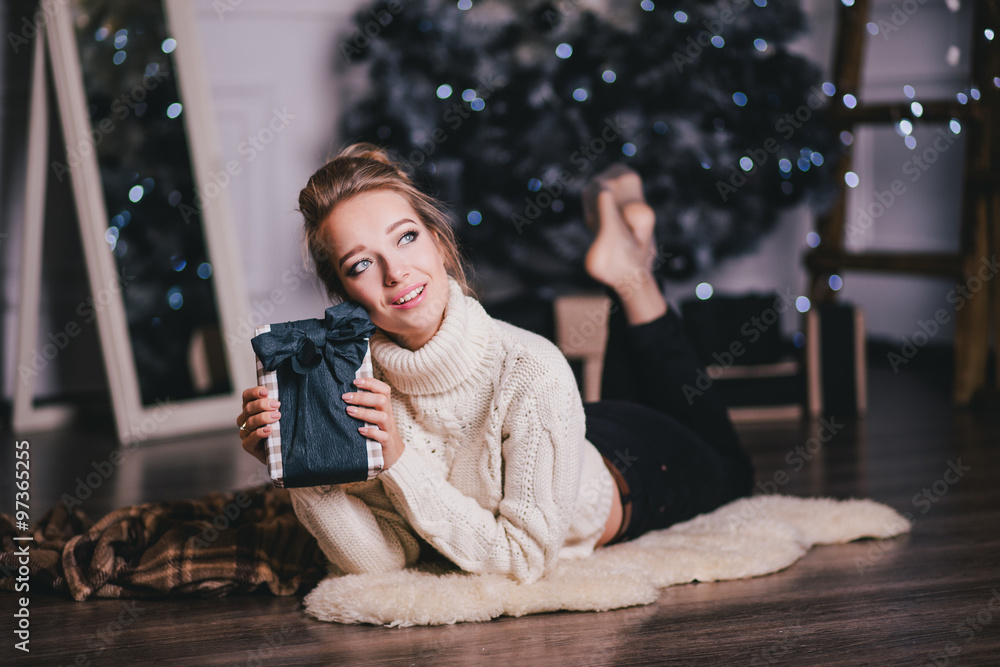 Beautiful young woman posing under Christmas tree in a holiday interior Beautiful young woman posing under Christmas tree in a holiday interior