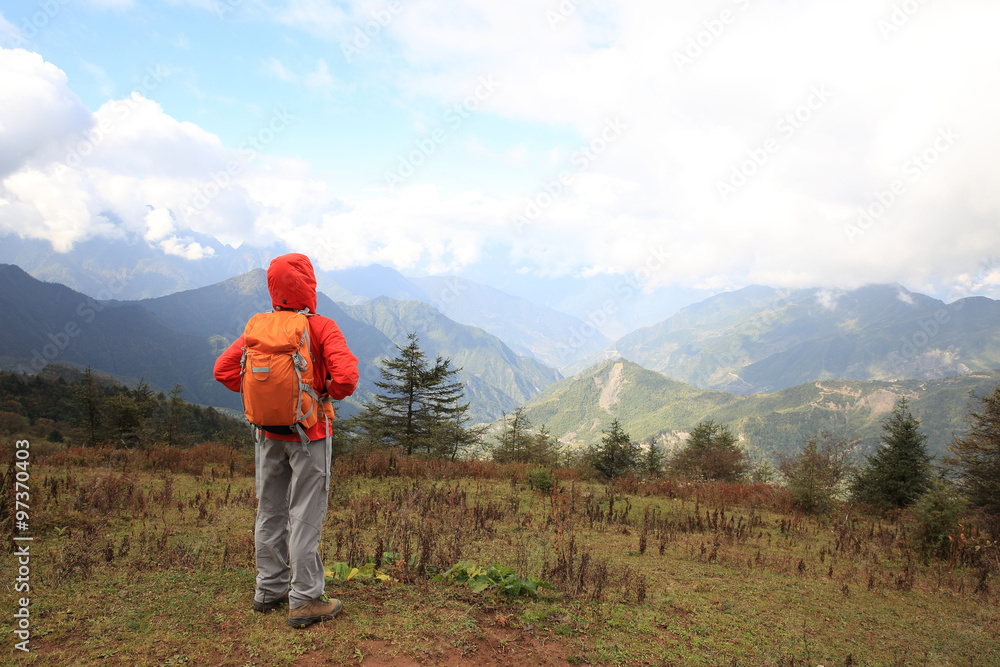 young determined woman backpacker hiking on mountain peak