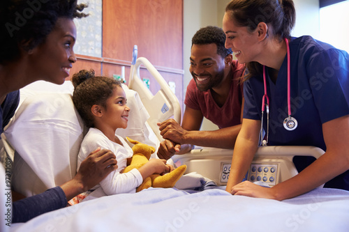 Pediatrician Visiting Parents And Child In Hospital Bed photo