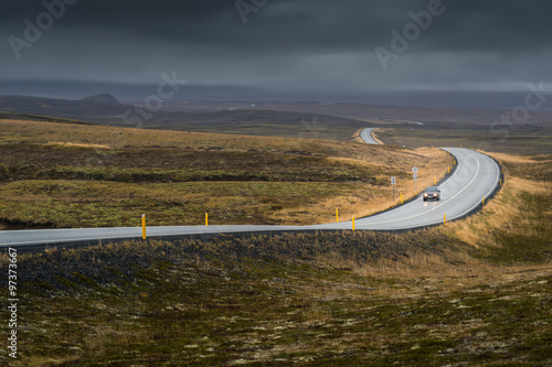 Curve line road with lonely car in Autumn season in cloudy day