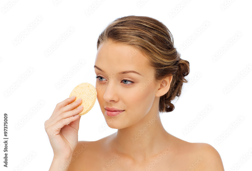 young woman cleaning face with exfoliating sponge young woman cleaning face with exfoliating sponge