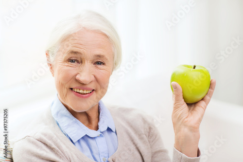 happy senior woman with green apple at home