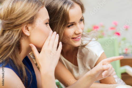 smiling young women gossiping at outdoor cafe photo