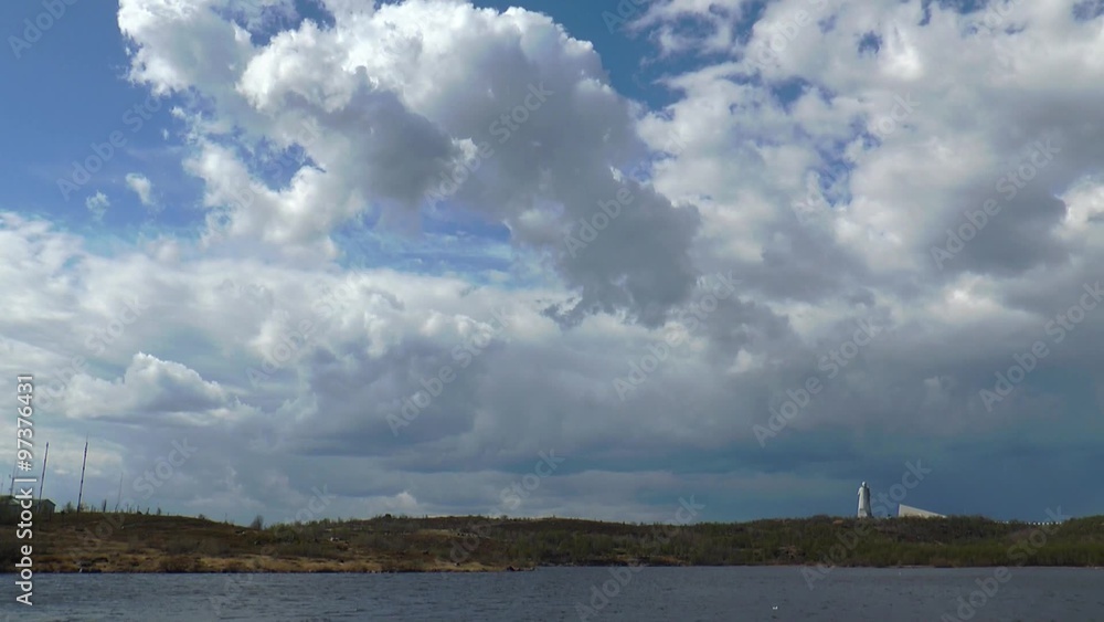 Moving blue-white smoky clouds on a spring day over the landscape of the tundra and lake and visible from afar monument, timelapse. Moving blue-white smoky clouds on a spring day over the landscape of the tundra and lake and visible from afar monument, timelapse.