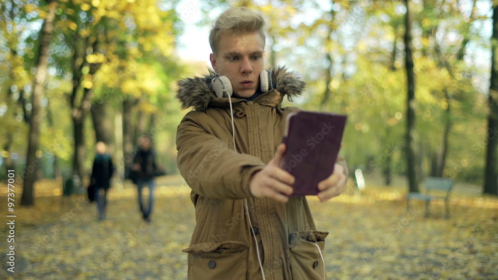 Man doing selfies on tablet in the autumnal park, steadycam shot
Man doing selfies on tablet in the autumnal park, steadycam shot