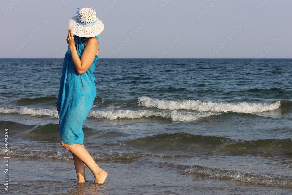 Girl in a blue pareo and hat on the beach