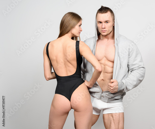 Beautiful couple of bodybuilder and fitness women posing on grey background