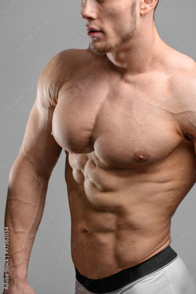 Fototapeta premium Close up shot without face of athletic man over grey background