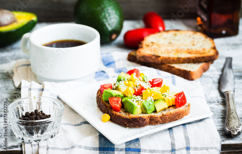 toast with fresh avocado, tomato and corn, a cup of coffee, brea