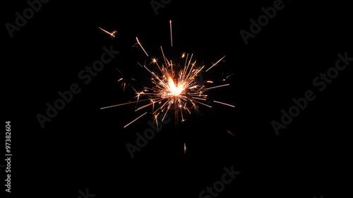 Wallpaper Mural Centrally positioned firework sparkler burning isolated. Gun powder sparks shot against deep dark background Torontodigital.ca
