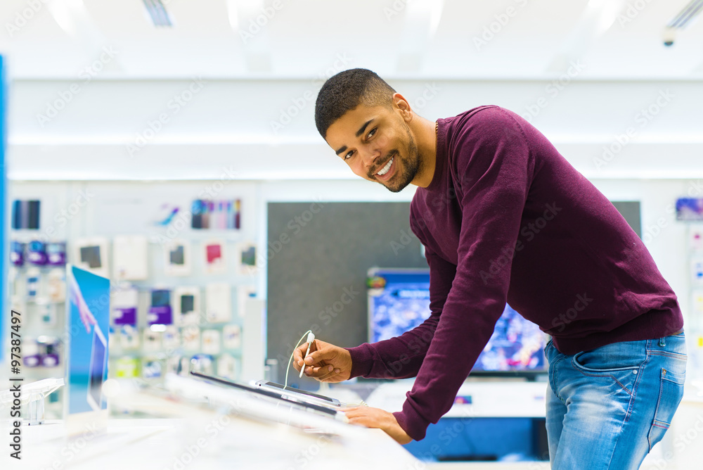 Handsome man looking for new tablet. He is using pencil for tablet computer. Tech shop. Handsome man looking for new tablet. He is using pencil for tablet computer. Tech shop.