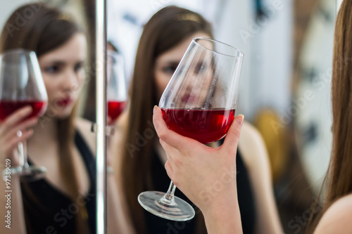 Девушка держит в руке бокал с красным вином
