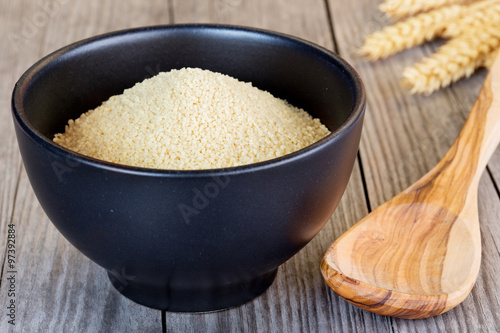 couscous in a black bowl and wooden spoon