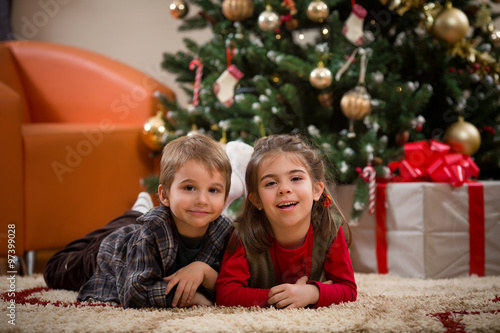 Cute happy children lying on the floor in front of the Christmas tree