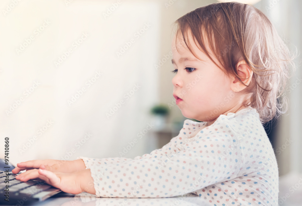 Little toddler girl typing on a computer