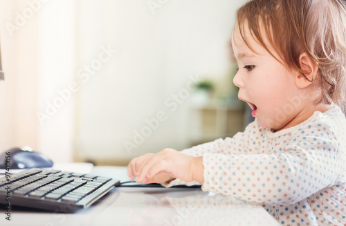 Happy excited toddler girl using her computer