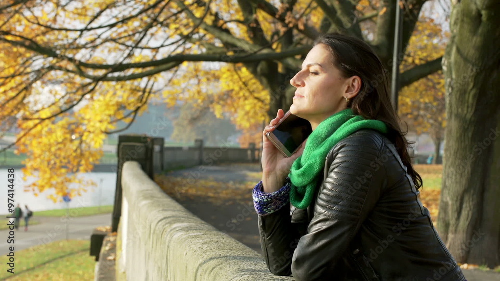 Woman standing on boulevard at autumn and chatting on cellphone
Woman standing on boulevard at autumn and chatting on cellphone