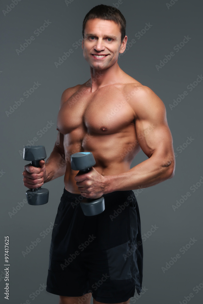 Shirtless bodybuilder holding pair of dumbells. Shirtless bodybuilder holding pair of dumbells.