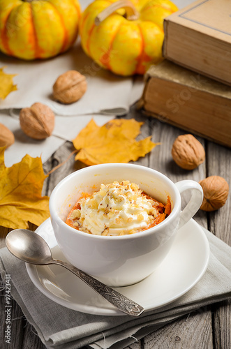 Pumpkin dessert in a mug prepared in microwave on an autumn background 