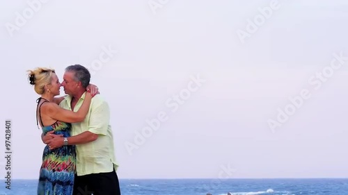 An older couple kiss on the beach