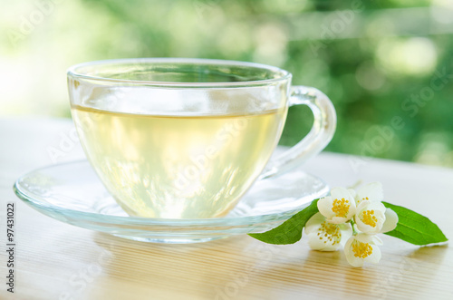 Glass cup of tea with jasmine on the wooden background