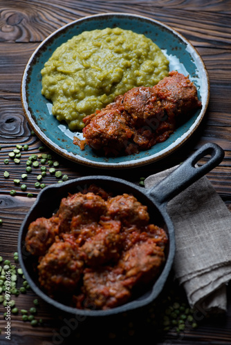 Meatballs in tomato sauce with boiled green peas, studio shot