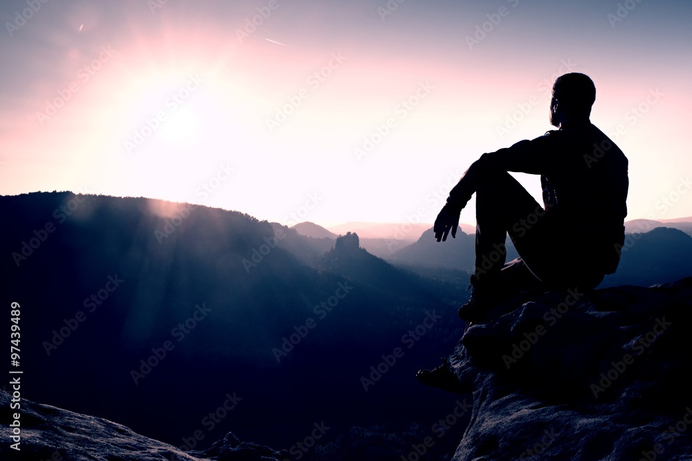 Hiker take relaxing on a rock and enjoying sunset at horizon. Vivid effect. Hiker take relaxing on a rock and enjoying sunset at horizon. Vivid effect.