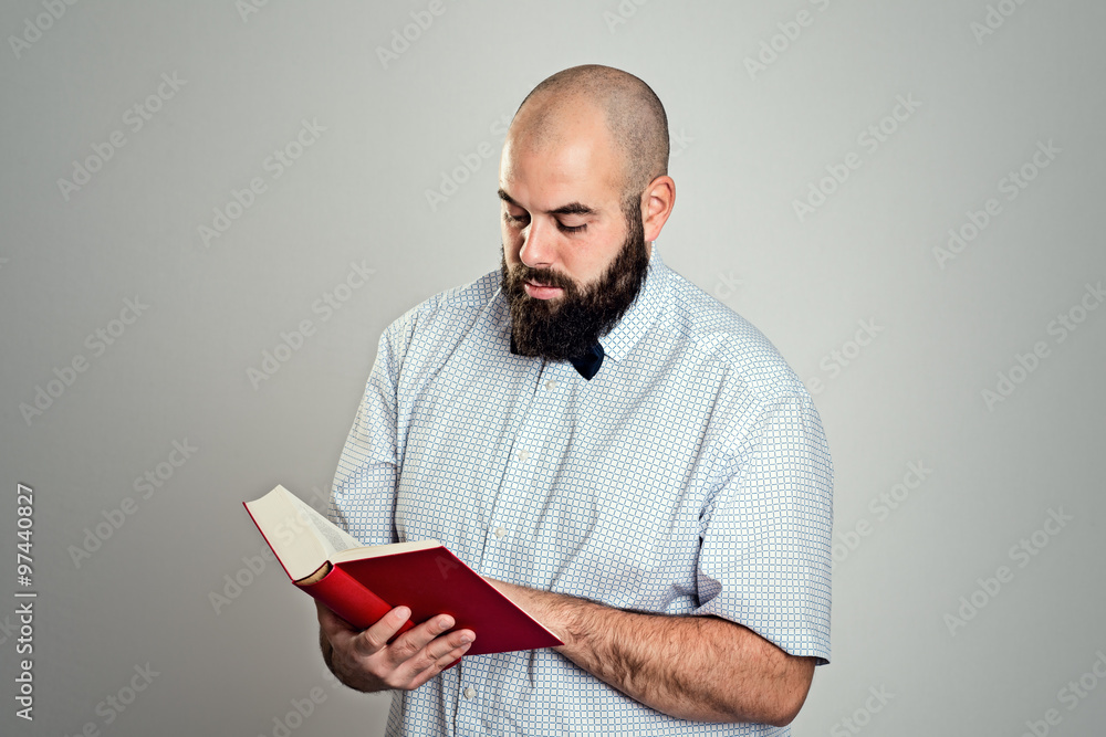 bearded man reading a book in front of gray background bearded man reading a book in front of gray background