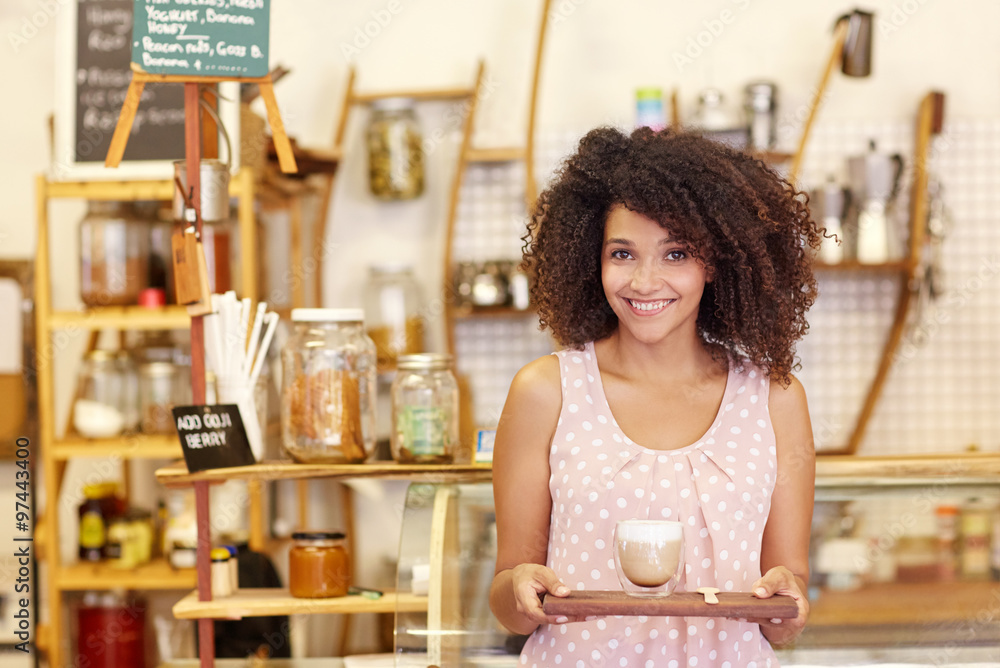 Beautiful waitress bringing a latte on a wooden tray in a modern