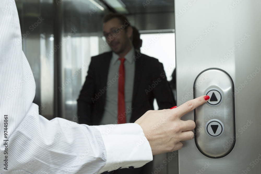 Female hand pressing elevator up button. Businessman inside of the elevator.