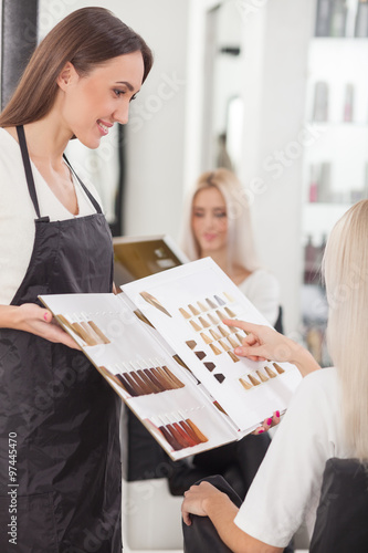 Pretty young hairdresser is serving her customer