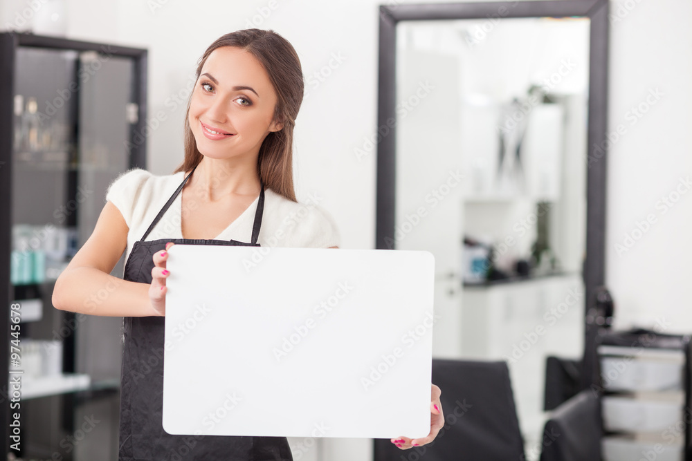 Cheerful female hairdresser is showing a placard Cheerful female hairdresser is showing a placard
