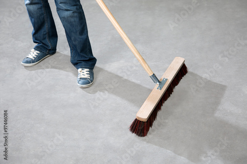 Eine Frau reinigt mit einem grossen Besen den Boden vor einem Hotel