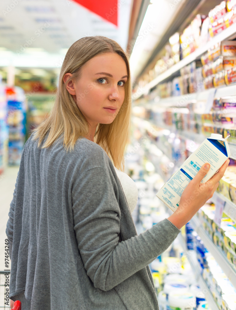 Woman choosing milk in grocery store.