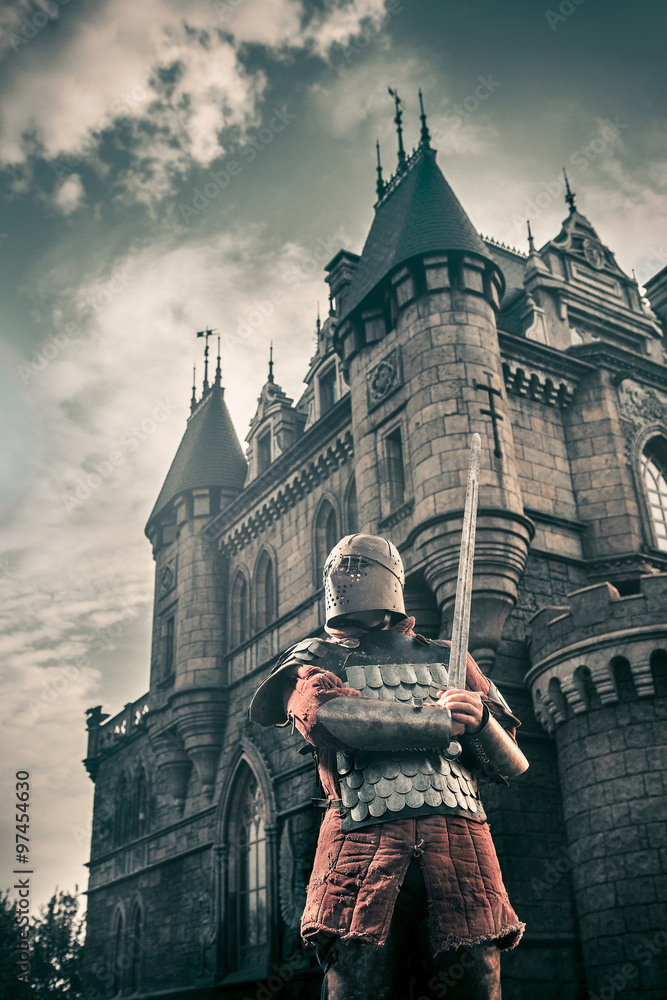 Fototapeta premium Medieval knight with the sword on the ancient castle background