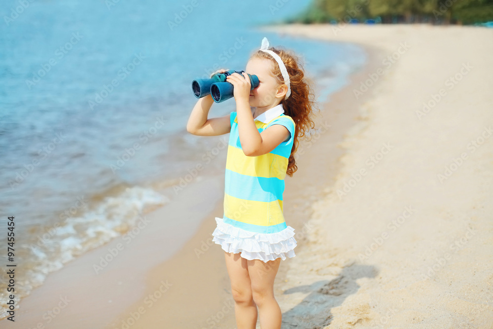 Little girl child looks in binoculars on beach near sea Little girl child looks in binoculars on beach near sea