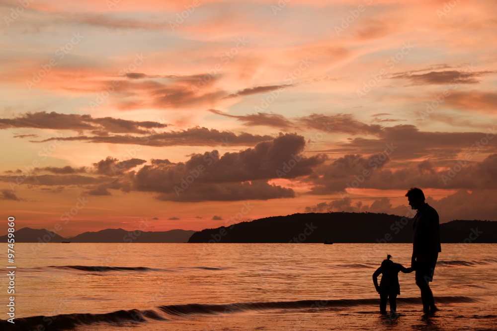 Silhouette image of father and his child by the sea shore, sunset
