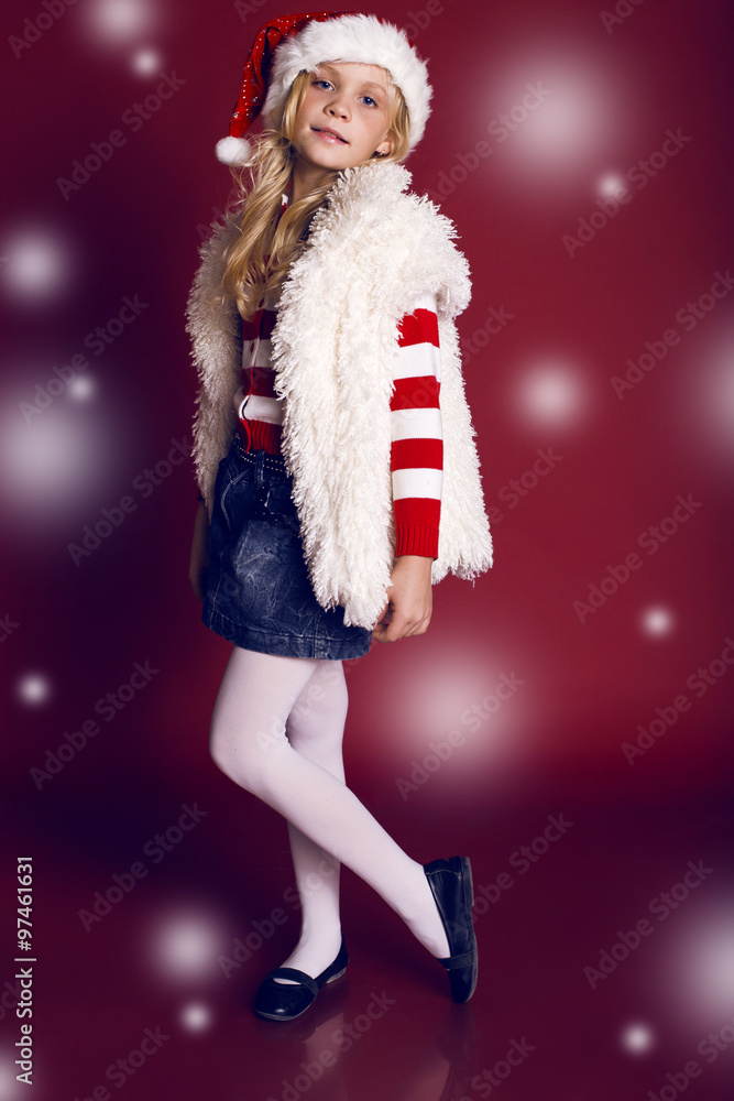 Holiday photo of beautiful little girl with blond hair holding Christmas presents and posing in studio Holiday photo of beautiful little girl with blond hair holding Christmas presents and posing in studio