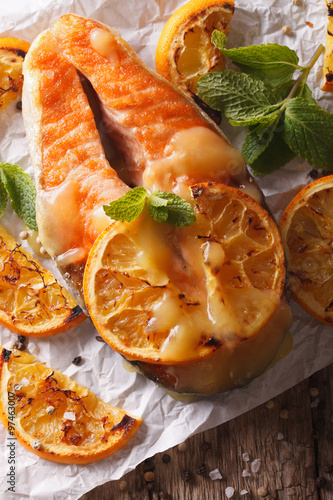 baked salmon with oranges close-up on the table. vertical top view
