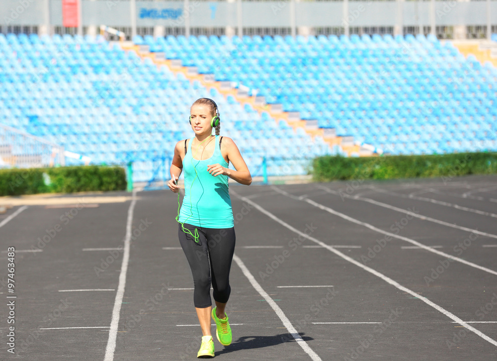 Fototapeta premium Young woman listening to music on the stadium