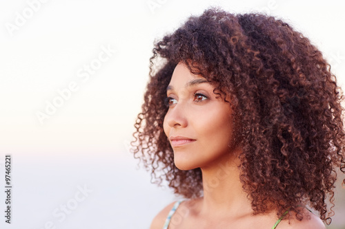 Mixed race woman with afro hair looking away serenely outdoors